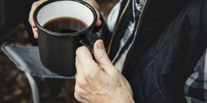 maos segurando uma xícara de café