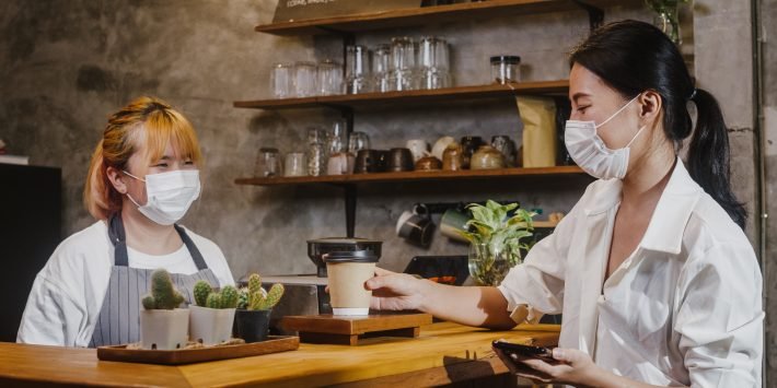 imagem duas mulheres de mascaras faciais em cafeteria