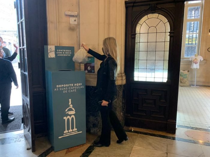 imagem mulher doando capsulas de cafe em recepiente no museu do cafe