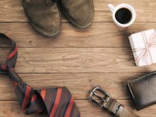 imagem xícara de café ao lado de sapatos e carteira gravata sobre a mesa de madeira