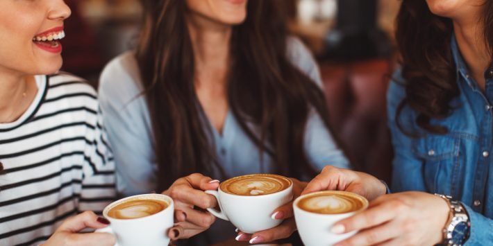 Three young women enjoy coffee at a coffee shop
