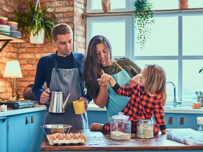Family together cooking breakfast in loft style kitchen.